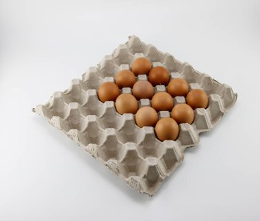 Beyaz arkaplana yerleştirilmiş karton bir kutuya yerleştirilmiş yumurtalar.