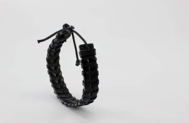 Beyaz arka plana takılmış siyah deri bir bilezik..