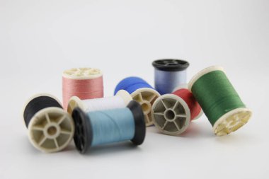 Beyaz arkaplana yerleştirilmiş çeşitli renkli dikiş iplikleri.