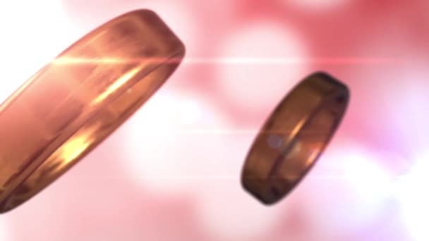 2 anillos de boda dorados que se fusionan con un hermoso fondo rosa bokeh — Vídeos de Stock