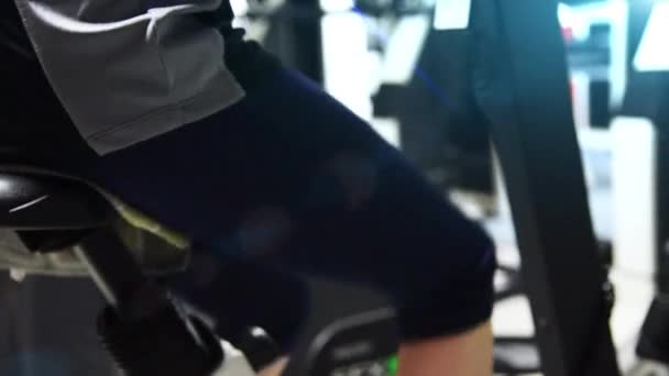 Een meisje uit te oefenen op een upright bike in een sportschool. — Stockvideo