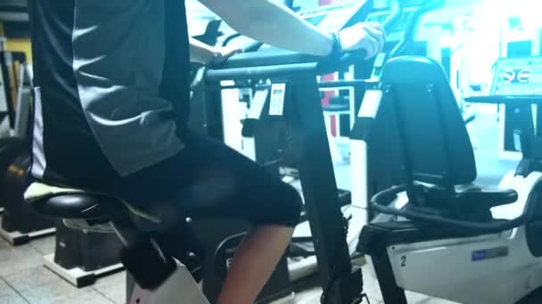 Ένα κορίτσι άσκηση σε στατικό ποδήλατο σε ένα γυμναστήριο. — Αρχείο Βίντεο