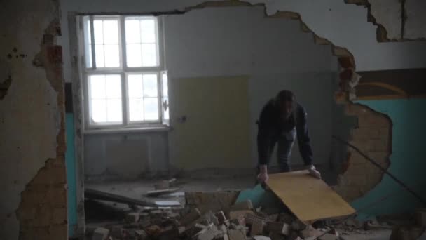 Deprimido e louco homem joga bordo no chão em uma casa abandonada — Vídeo de Stock