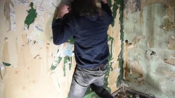 Un uomo depresso e pazzo colpisce contro il muro in una casa abbandonata — Video Stock