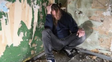 Depresyonda ve öfkeli adam terk edilmiş bir evde köşede oturuyor