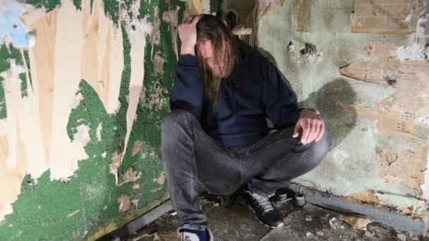 Deprimeret og vred mand sidder i hjørnet i et forladt hus – Stock-video