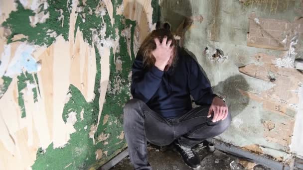 Deprimeret og vred mand sidder i hjørnet i et forladt hus – Stock-video