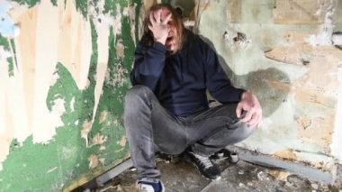 Depresyonda ve öfkeli adam terk edilmiş bir evde köşede oturuyor