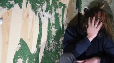 Depresyonda ve öfkeli adam terk edilmiş bir evde köşede oturuyor