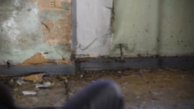 Depresyonda ve deli bir adam terk edilmiş bir evde bir kanepede oturuyor ve aynaya bakar