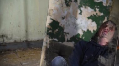Depresyonda ve deli bir adam terk edilmiş bir evde bir kanepede oturuyor ve aynaya bakar