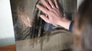 Depresyonda ve kızgın bir adam eski terk edilmiş bir evde kirli aynaya üzerinden elini mendil