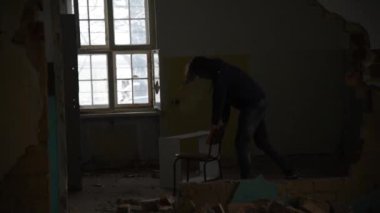 Depresyonda ve öfkeli adam huzursuz eski terk edilmiş bir evde bir sandalyede arkasında duruyor