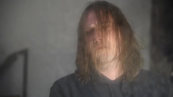 Un homme déprimé et en colère est assis devant son reflet dans une vieille maison abandonnée 