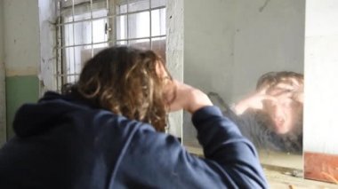 Depresyonda ve öfkeli adam önünde onun yansıması bir eski terk edilmiş evde oturuyor