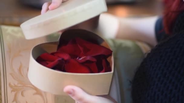 Valentinstagsgeschenk. junges Mädchen öffnet Herz Geschenkbox mit Rosenblättern — Stockvideo