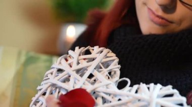 Sevgililer hediye. Gül yaprakları ile beyaz ahşap kalp tutan genç kız