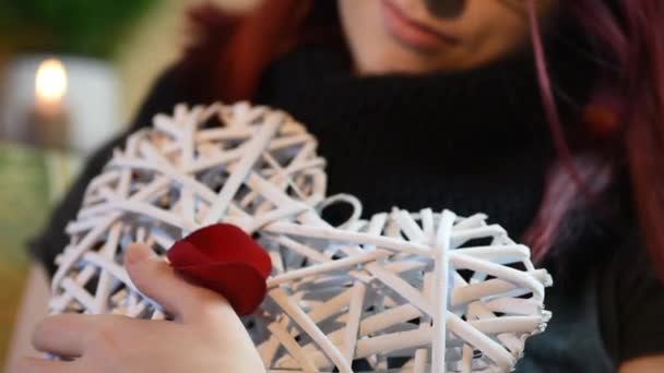 Valentinstagsgeschenk. junges Mädchen mit weißem Holzherz mit Rosenblättern — Stockvideo