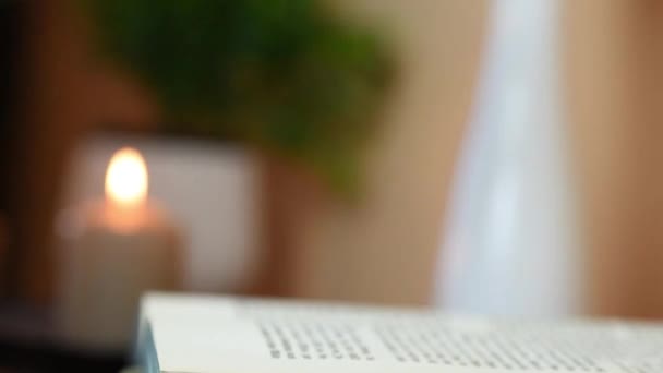 Da vicino raccogliendo una rosa rossa dal tavolo con libro e candele — Video Stock