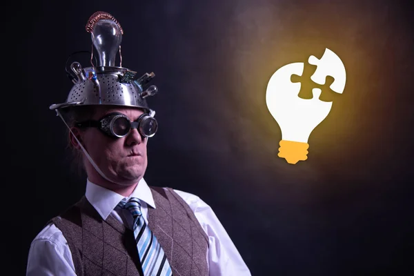 Grappige nerd of geek met aluminium hoed op zoek naar gloeilamp met een idee — Stockfoto