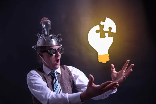 Grappige nerd of geek met aluminium hoed op zoek naar gloeilamp met een idee — Stockfoto