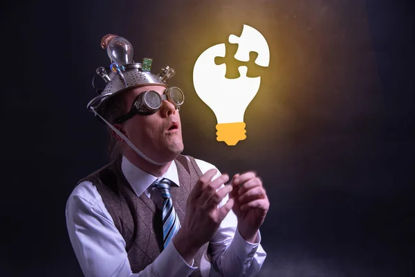 Funny nerd or geek with aluminium hat looking to light bulb having an idea