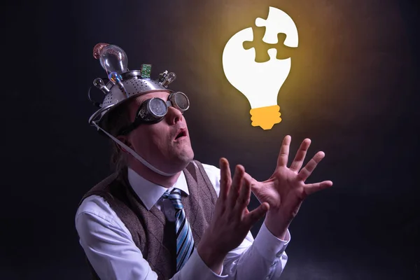 Funny nerd or geek with aluminium hat looking to light bulb having an idea