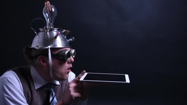 Nerd con sombrero de aluminio mira su tableta — Vídeo de stock