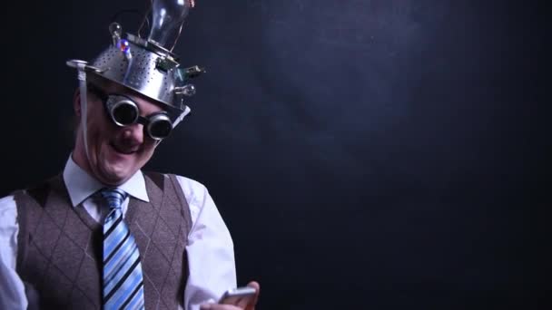 Nerd avec chapeau en aluminium regarde en amour avec son téléphone portable — Video