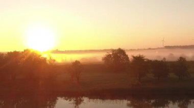 Güzel gündoğumu ile ağaçlar ile sisli göl ve çayır üzerinde Uçuş