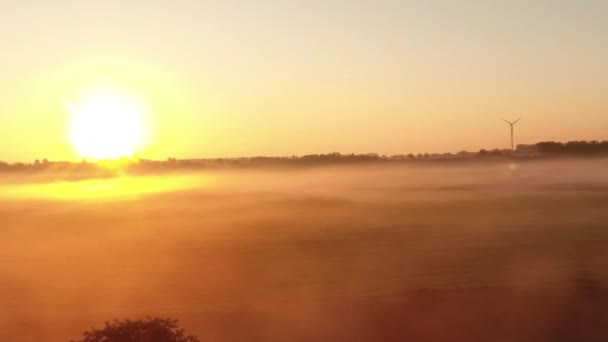 Voo sobre campos nublados com o nascer do sol e turbinas eólicas — Vídeo de Stock