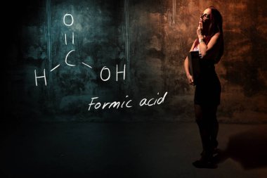 Seksi kız veya sekreter veya kadın öğrenci formik asit handdrawn kimyasal formülü sunan
