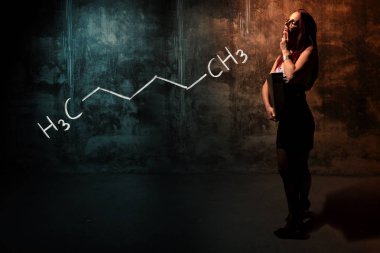 Seksi kız veya sekreter ya da kadın öğrenci heksane handdrawn kimyasal formülü sunan