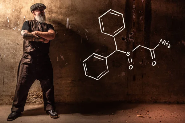 Bearded old man presenting handdrawn chemical formula of Modafinil