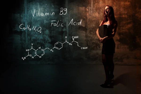 Sexy chica o secretaria o estudiante que presenta fórmula química dibujada a mano de vitamina B9 — Foto de Stock