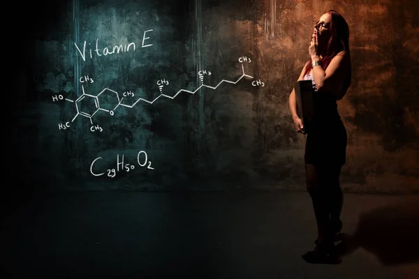 Sexy meisje of secretaresse of vrouwelijke student presenteren hand getekende chemische formule van vitamine E — Stockfoto