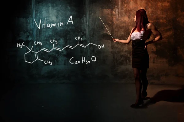 Сексуальная девушка или секретарь или студентка, представляющая химическую формулу витамина А, нарисованную вручную — стоковое фото