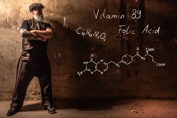 Hombre viejo barbudo que presenta fórmula química dibujada a mano de vitamina B9 — Foto de Stock