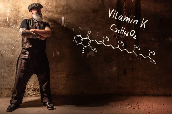 Hombre viejo barbudo que presenta fórmula química dibujada a mano de vitamina K — Foto de Stock