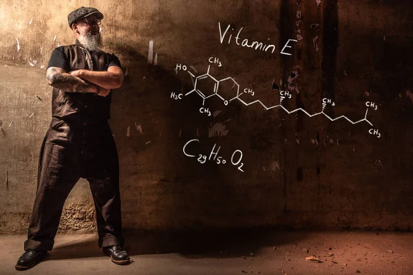 Bearded old man presenting handdrawn chemical formula of Vitamin E