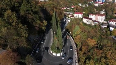 Bir yol yeşil orman yamaçları ve karlı dağın tepesinde bir arka plan üzerinde yılan gibi. Dağ Olimpiyat Köyü, Sochi giden yol.