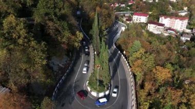 Bir yol yeşil orman yamaçları ve karlı dağın tepesinde bir arka plan üzerinde yılan gibi. Dağ Olimpiyat Köyü, Sochi giden yol.