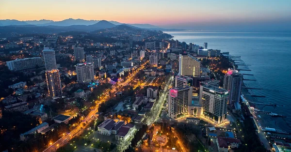 Üstten görünüm akşam şehir Sochi ışıklar, modern evler ve deniz ile. Havadan görünümü