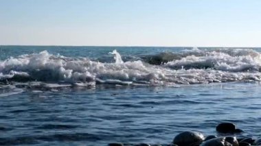 Deniz dalgalarının yavaş hareket çekim hareketi. Dalgalar kayalara karşı çöküyor. Sprey farklı yönde uçuyor. Su yavaş hareket.