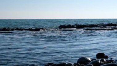 Deniz dalgalarının yavaş hareket çekim hareketi. Dalgalar kayalara karşı çöküyor. Sprey farklı yönde uçuyor. Su yavaş hareket.