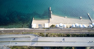 Deniz sahilindeki sahil Iskelesi sahilde, arabaların plaj boyunca nereye giteceği yolu. Plajdaki güneşten şemsiye. Yüzme alanı insan yok. Temiz plaj. Quadcopter ile hava fotoğrafçılığı