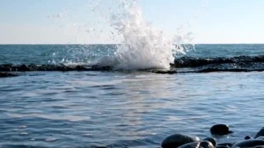 Deniz dalgalarının yavaş çekim hareketi. Skyline. Mavi gökyüzü ve su. Sakin bir deniz var. Kıyıda dalgalar kırılıyor.