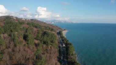 Mavi denizin kuş bakışı görünümünden havadan video. Deniz den bir tatil köyü. Kıyı boyunca uçuyor. Turkuaz renginden berrak deniz. Dağların üzerinde gökyüzünde bulutlar. Rusya'nın Soçi tatil köyü.
