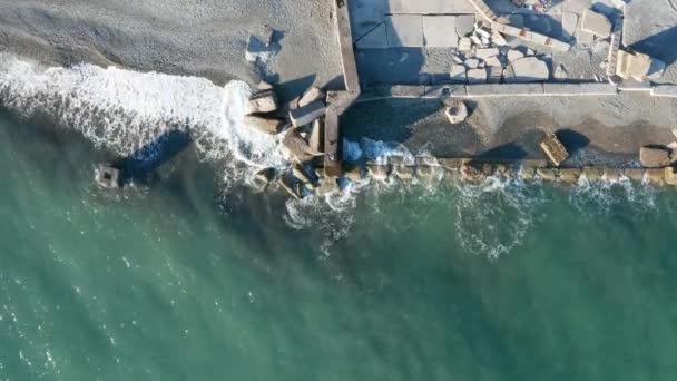 航空写真撮影 カメラを下向きにしています 波は海岸の岩に割れる 人々は海の上を歩く 屋外レクリエーション 大きな防波堤が波を止める — ストック動画