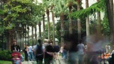 Timelapse çekim video. Soçi'nin merkezinde bir yaya caddesinde çok sayıda insan yürüyor. Şehirde palmiye ağaçları ve yeşil çimenler yetişir. Uzaklaştırma.